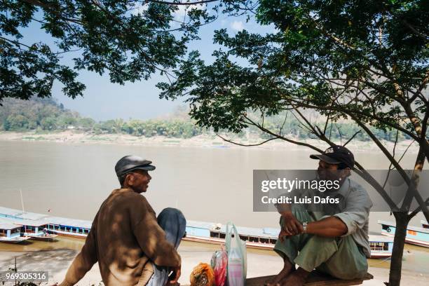 laotian men sitting by the mekong river - laotiaanse cultuur stockfoto's en -beelden