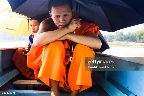 buddhist monks on a rowboat - laotian culture stock-fotos und bilder