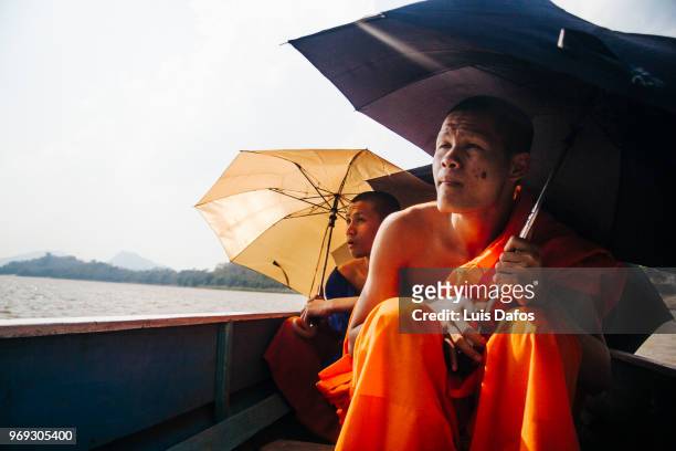 buddhist monks on a rowboat - laotian culture stock-fotos und bilder