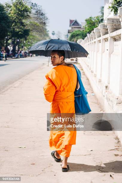 buddhist monk with umbrella - laotian culture stock-fotos und bilder