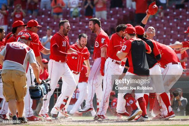 Jesse Winker of the Cincinnati Reds celebrates with teammates after hitting a two-run home run to win the game in the 13th inning against the...