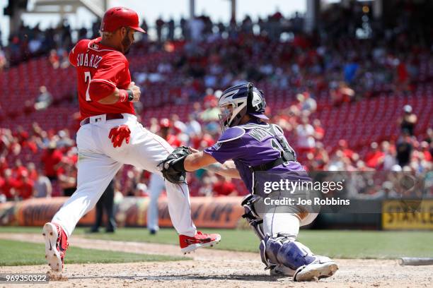 Eugenio Suarez of the Cincinnati Reds gets tagged out at home plate by Tony Wolters of the Colorado Rockies while trying to score in the eighth...