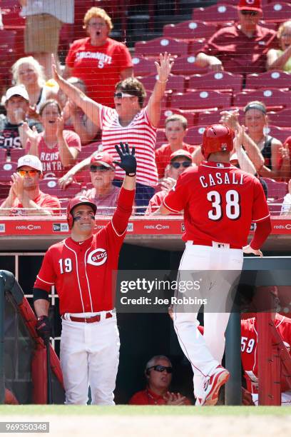 Joey Votto of the Cincinnati Reds congratulates Curt Casali after he scored on a wild pitch by Wade Davis of the Colorado Rockies to tie the game in...