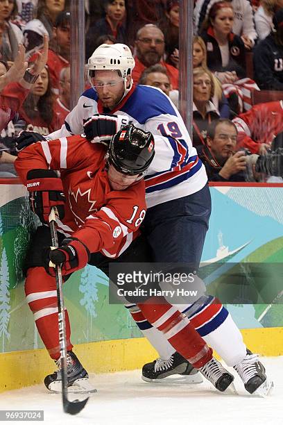 Michael Richards of Canada attempts to control the puck against Ryan Whitney of the United States during the ice hockey men's preliminary game...