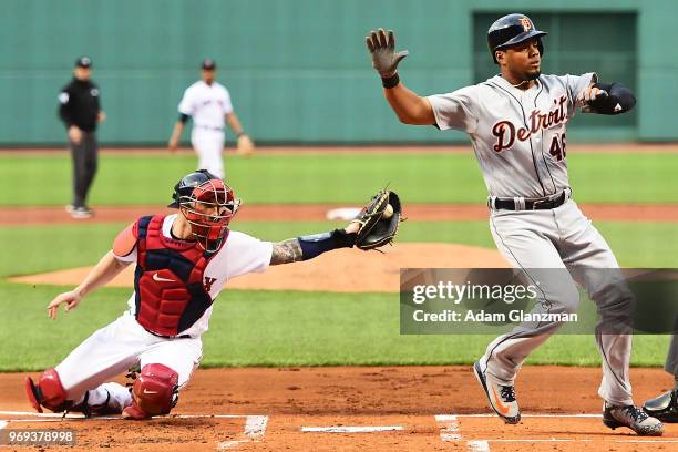 Jeimer Candelario of the Detroit Tigers is safe at home plate as he avoids the tag of Blake Swihart of the Boston Red Sox in the first inning of a...