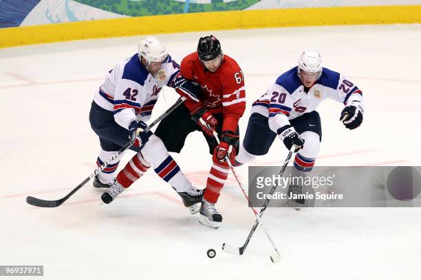 Rick Nash of Canada attempts to control the puch against David Backes and Ryan Suter of the United States during the ice hockey men's preliminary...