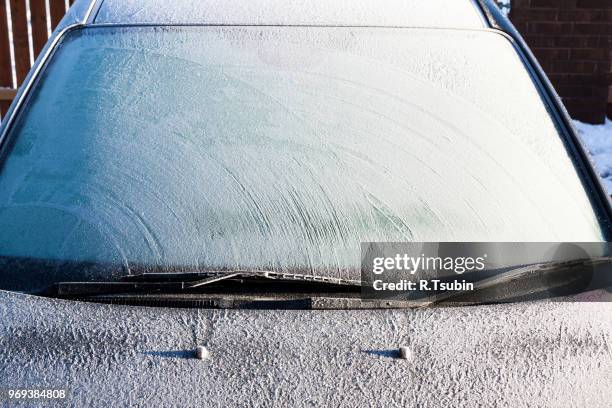 frosty patterns on a completely covered car windscreen - winter car window stock-fotos und bilder