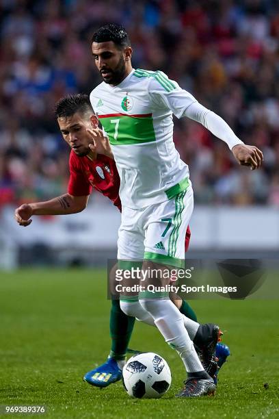 Riyad Mahrez of Algeria is challenged by Raphael Guerreiro of Portugal during the friendly match of preparation for FIFA 2018 World Cup between...
