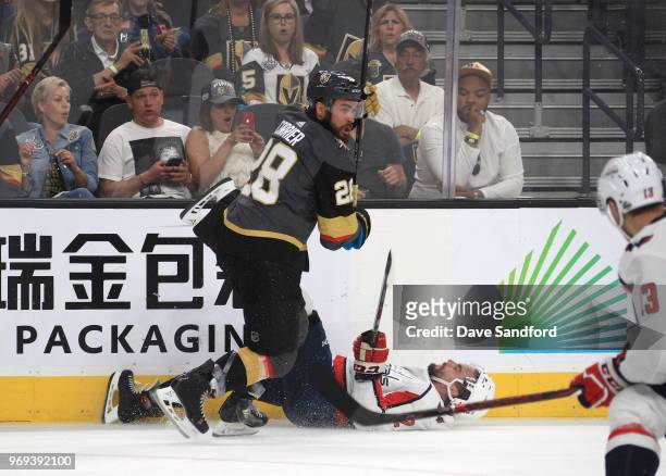 Matt Niskanen of the Washington Capitals falls to the ice after a check by William Carrier of the Vegas Golden Knights along the side boards in the...