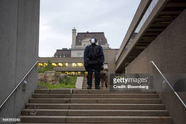 Police officer in riot gear stands with a police dog outside the National Assembly of Quebec during a demonstration ahead of the Group of Seven...