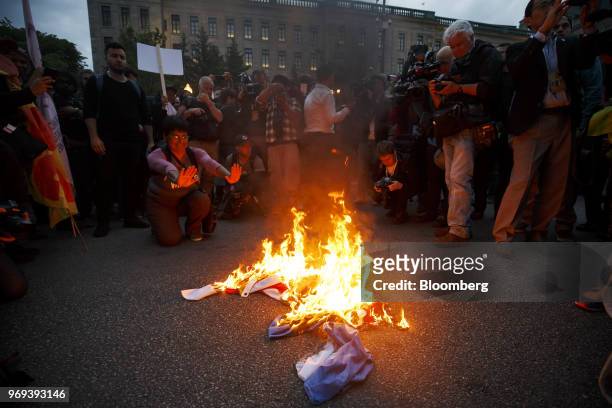 An American flag burns outside the National Assembly of Quebec during a demonstration ahead of the Group of Seven Leaders' Summit in Quebec City,...
