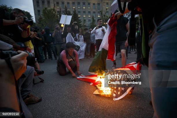 Protesters burn an American flag and an Italian national flag outside the National Assembly of Quebec during a demonstration ahead of the Group of...