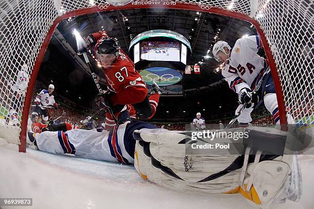 Sidney Crosby of Canada trips over goalie Ryan Miller of the United States during the ice hockey men's preliminary game between Canada and USA on day...