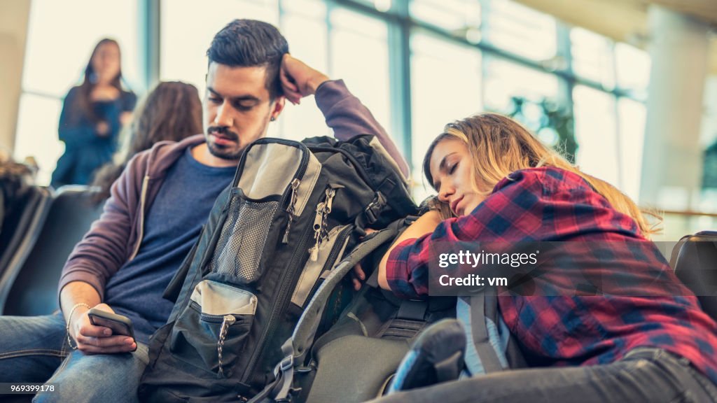 Junge Erwachsene Paar an einem Flughafen-Lobby wartet