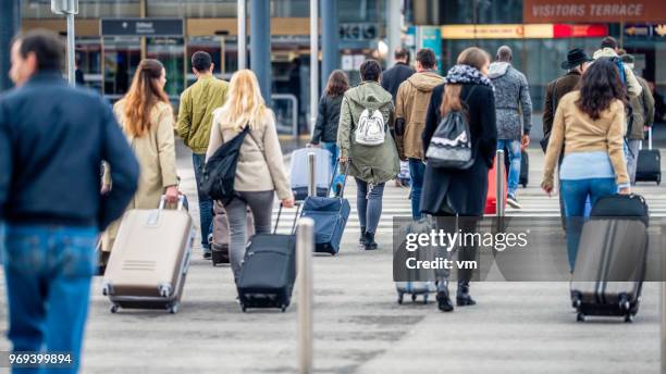 menschen zu fuß in richtung flughafen - auswanderung und einwanderung stock-fotos und bilder