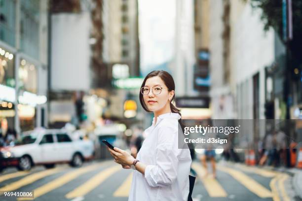 portrait of smart asian businesswoman using mobile phone in busy downtown city street - smart casual - fotografias e filmes do acervo