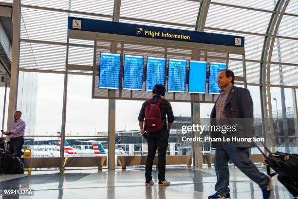 man looking for flight at timetable in departure lounge of o'hare international airport - le lounge stockfoto's en -beelden