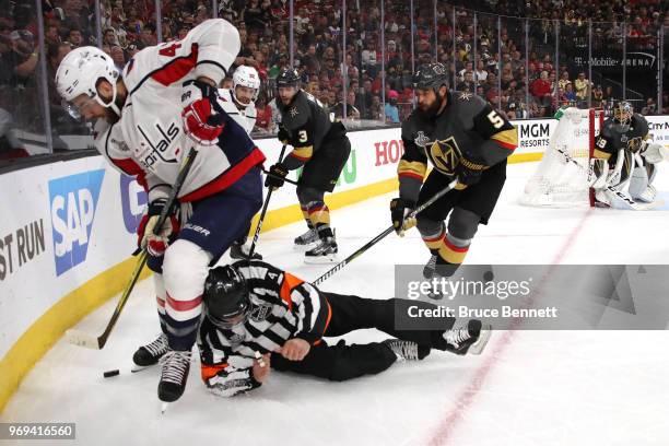 Referee Wes McCauley gets tripped up as Tom Wilson of the Washington Capitals and Deryk Engelland of the Vegas Golden Knights battle for the puck...