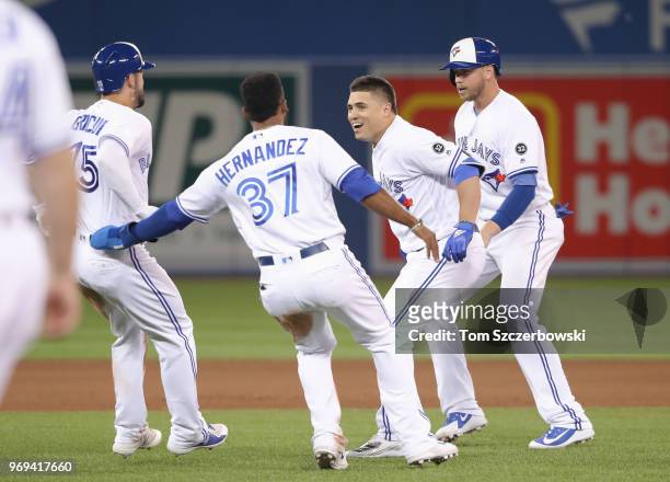 Aledmys Diaz of the Toronto Blue Jays is congratulated by teammates after hitting a game-winning RBI single in the tenth inning during MLB game...