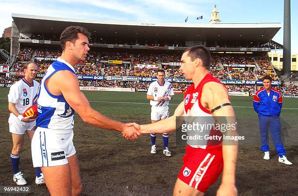 Wayne Carey of the Kangaroos and Paul Kelly of the Swans shake hands prior to both playing in their 150th match during the round 13 match between...