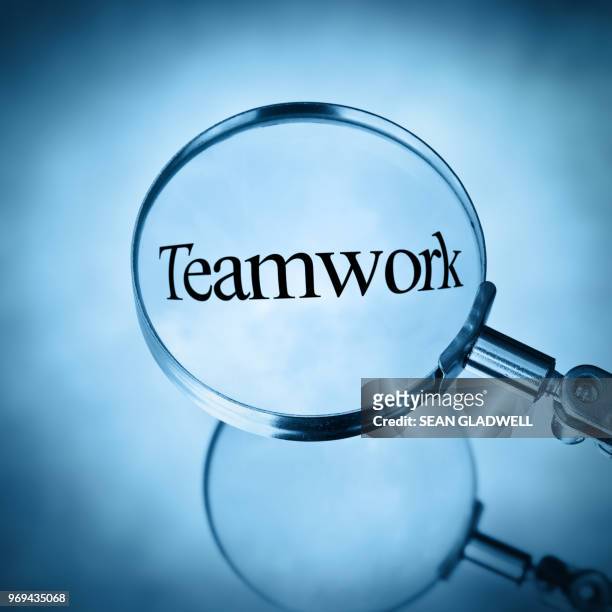 the word teamwork magnified under magnifying glass - help engels woord stockfoto's en -beelden