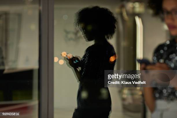 reflection of young businesswoman checking smartphone in the office at night - foco difuso fotografías e imágenes de stock