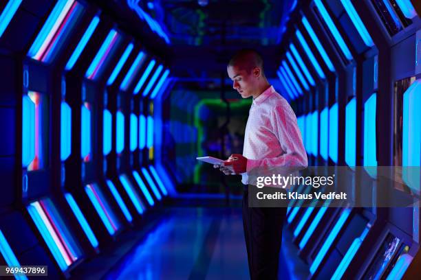 young businessman looking at digital tablet in spaceship like corridor - business cloud stock-fotos und bilder