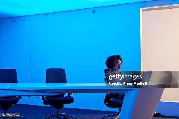 businesswoman working on laptop in meeting room at night - girl side view stockfoto's en -beelden