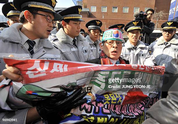 Policemen block a South Korean activist holding an anti-Japanese banner in front of the Japanese embassy in Seoul on February 22, 2010 during a...