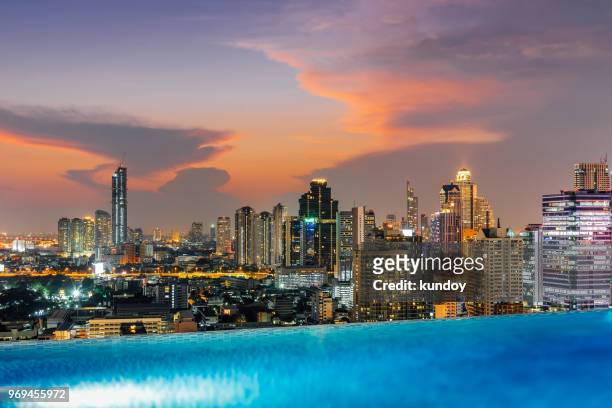 skyline view of modern building in business district center with swimming pool foreground at sunset. - rooftop pool imagens e fotografias de stock