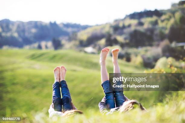 two school girls lying on the grass in spring nature, with their feet up. - barefoot child stock pictures, royalty-free photos & images