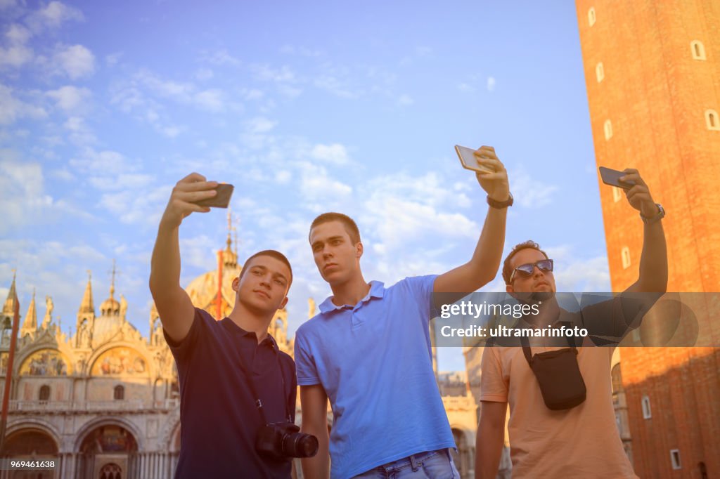 Tourists in Venezia. Three young men, have fun. Group of friends taking a  photo with smartphone, St Mark's Cathedral in Piazza San Marco, Venice. Casual lifestyles Urban scene Italy.  Visiting Venice, Italy.