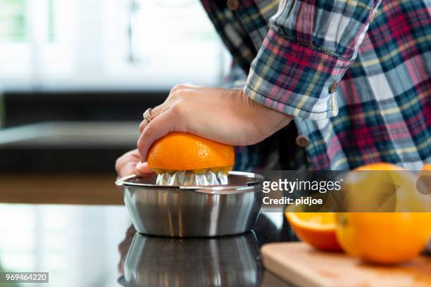 close-up van handen van een vrouw knijpen sinaasappelen voor sap - orange juice stockfoto's en -beelden