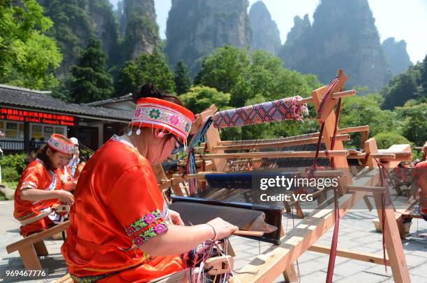 Chinese women of Tujia ethnic group make Tujia Brocade, also known as Xilankapu, to welcome the 13th National Cultural Heritage Day during a show at...