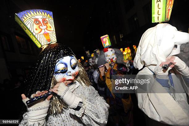 Revellers, wearing lanterns, play the flute as they parade through the streets of Basel during the traditional Morgestraich carnival on February 22,...