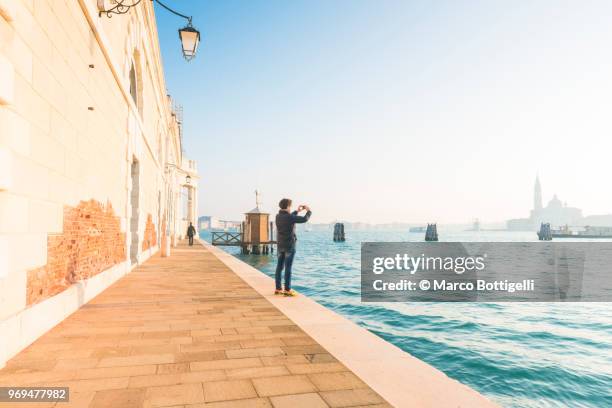 tourist taking a photo with smartphone in venice, italy - punta della dogana stockfoto's en -beelden