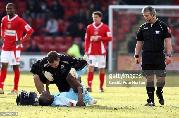 Abdul Osman of Northampton Town receives treatment from physio Stuart Barker as referee Peter Quinn looks on during the Coca Cola League Two Match...