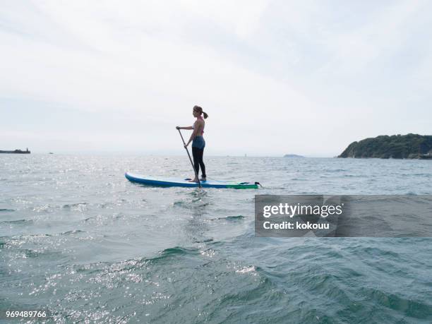 ハード支援ボードに乗って女性。 - paddleboarding ストックフォトと画像
