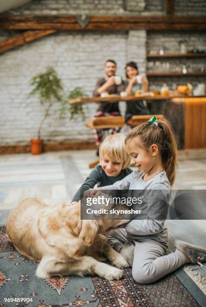 pequeños hermanos abrazando a su perro perdiguero de oro en alfombra en casa. - family children dog fotografías e imágenes de stock