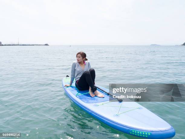 eine frau sitzt auf einem sub-brett im meer schwimmende. - funkwelle stock-fotos und bilder