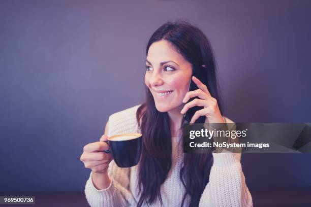 beautiful black hair woman in white sweater, sitting in cafe, drinking coffee, using mobile phone - no drinking stock pictures, royalty-free photos & images