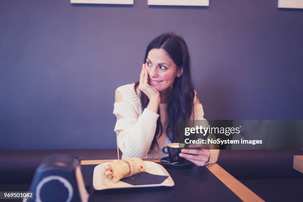 beautiful black hair woman in white sweater, sitting in cafe, drinking coffee, using mobile phone - no drinking stock pictures, royalty-free photos & images