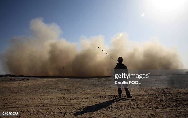 Marine stands guard as a landing helicopter churns up a cloud of dust in Marjah in Afghanistan's Helmand province on February 18, 2010. About 15,000...
