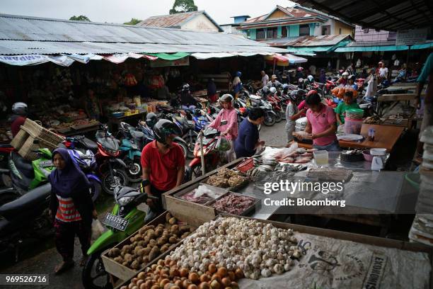 Fishmonger, center right, serves a customer as shoppers walk past vendors at stalls in Kapuas Hulu, West Kalimantan, Indonesia, on Friday, May 4,...