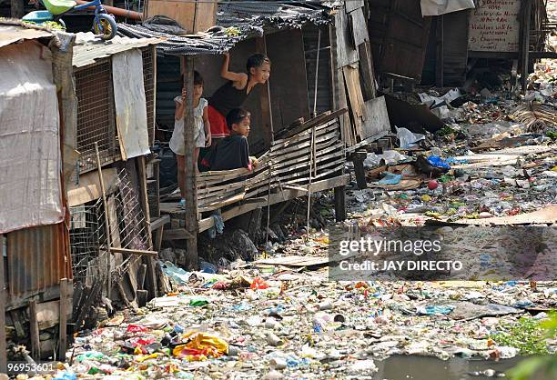 Children play along a polluted creekside shantytown in Manila on February 17, 2010. Twenty-one million Asians could fall back into extreme poverty...