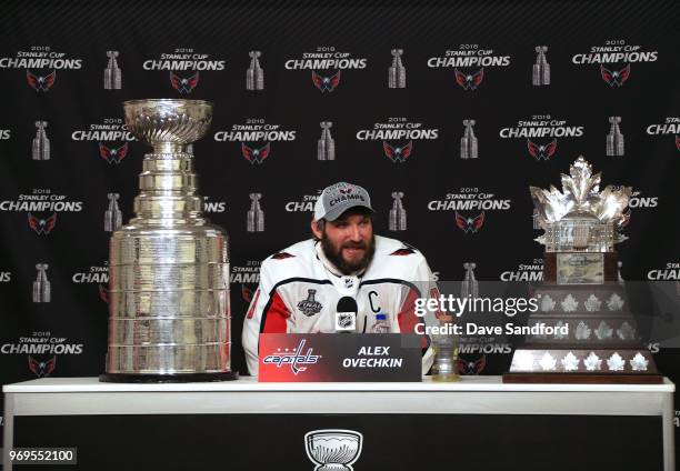 Alex Ovechkin of the Washington Capitals sits with the Conne Smythe Trophy and the Stanley Cup beside him during a press conference after Game Five...