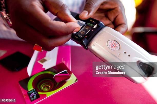 Man installs a Zain SIM card in his cell phone in a store in Kampala, Uganda, on Thursday, Feb. 18, 2010. Bharti Airtel Ltd., India's biggest...