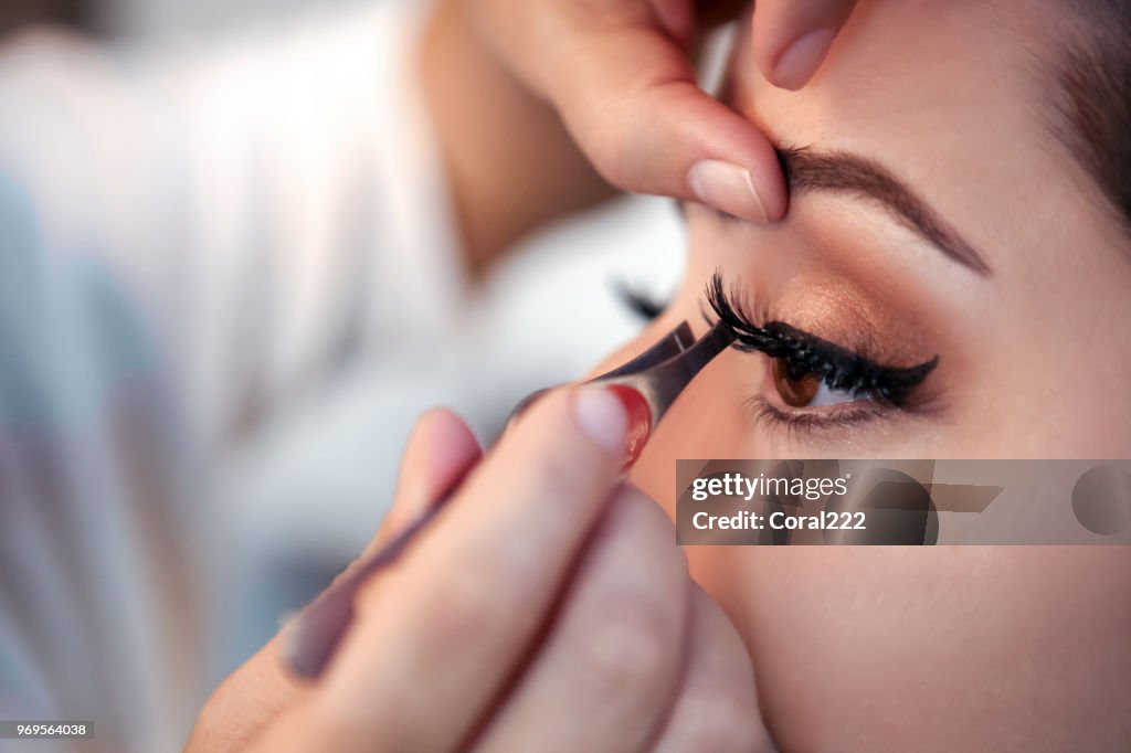 Makeup artist applying false eyelash
