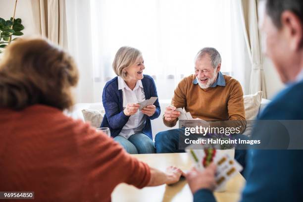 two senior couples playing a game of cards at home. - retirement card stock pictures, royalty-free photos & images