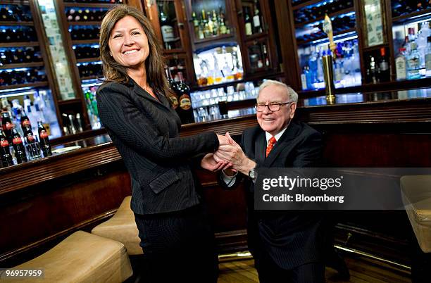 Warren Buffett, chief executive officer of Berkshire Hathaway, right, jokingly gets down on one knee as he holds the hand of Courtenay Wolfe, chief...